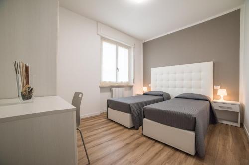 1 dormitorio con 2 camas, escritorio y ventana en Albergo Al Sole, en Castelnuovo del Garda