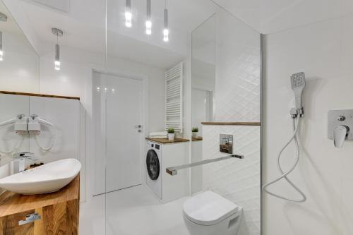 a white bathroom with a toilet and a sink at INA Rent - Tre Mare Apartamenty in Gdańsk