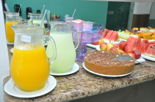 a table topped with glasses of orange juice and a cake at Bonjour Hotel in Macaé