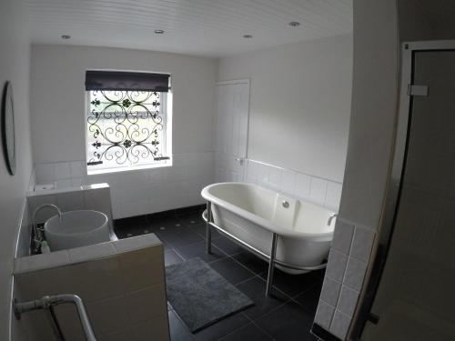 a white bathroom with a tub and a window at The Boathouse Wylam in Wylam