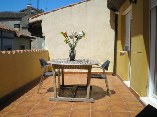 una mesa y sillas en un balcón con un jarrón de flores en Apartamentos Augusta Centro en Zaragoza