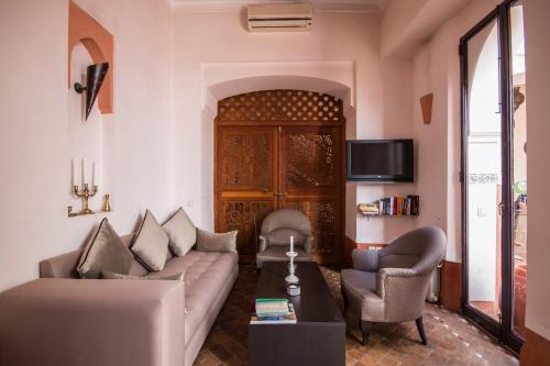 a living room with a couch and two chairs and a tv at Riad Soumia in Marrakesh