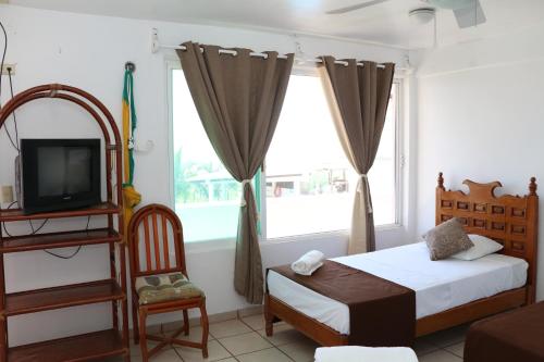 a bedroom with a bed and a tv and a chair at Hotel Arrecife Chachalacas in Chachalacas