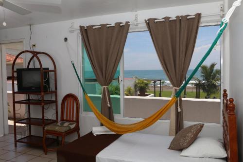 a bedroom with a hammock and a view of the ocean at Hotel Arrecife Chachalacas in Chachalacas