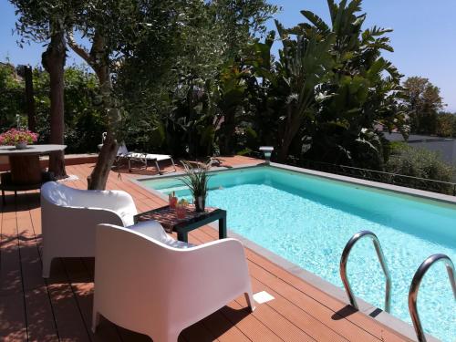 una piscina con sedie bianche e un tavolo accanto ad essa di Lily house a Gravina di Catania
