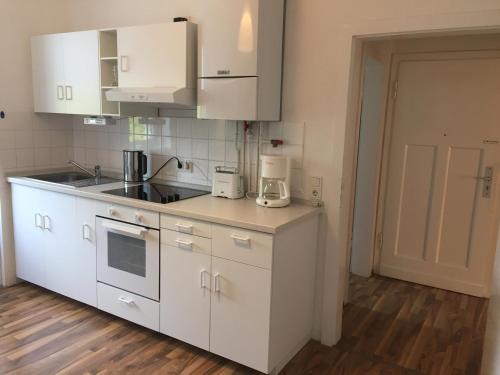 eine Küche mit weißen Geräten und Holzböden in der Unterkunft Lorenz Apartment in Hattingen