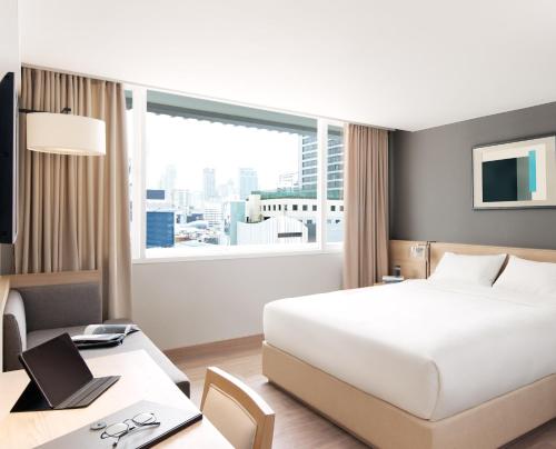 a hotel room with a bed and a desk with a laptop at Kritthai Residence in Bangkok
