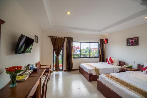 a hotel room with two beds and a television at Kouprey Hotel in Siem Reap