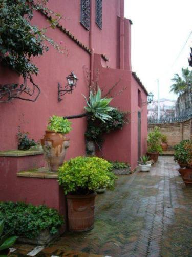a red building with potted plants on the side of it at Villa Chiarenza Maison d'Hotes in Giardini Naxos