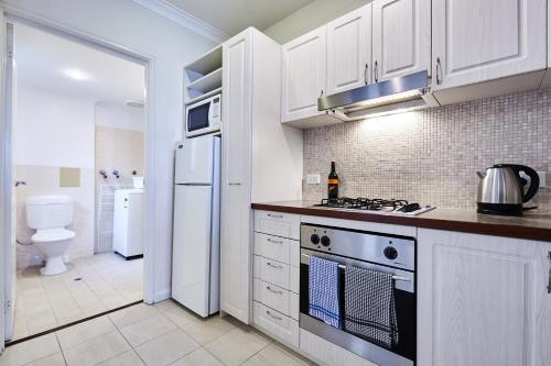 a kitchen with white cabinets and a stove top oven at Fremantle Townhouse u/5 in Fremantle