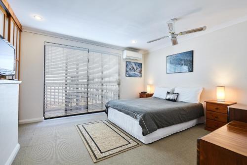 ein Schlafzimmer mit einem Bett und einem großen Fenster in der Unterkunft Fremantle Townhouse u/5 in Fremantle
