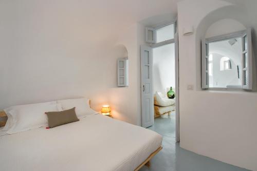 a white bedroom with a bed and a mirror at Artia Mansion in Oia