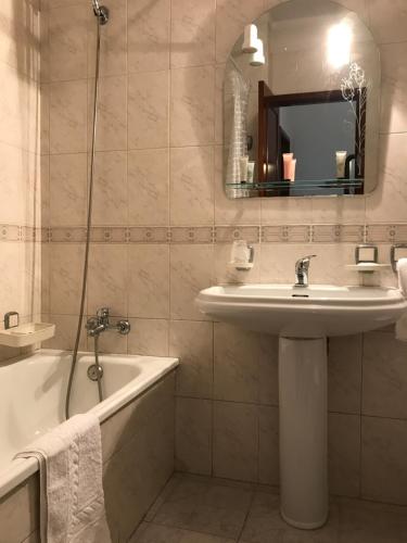 a bathroom with a sink and a tub and a mirror at Apartamento Praia da Amorosa in Viana do Castelo