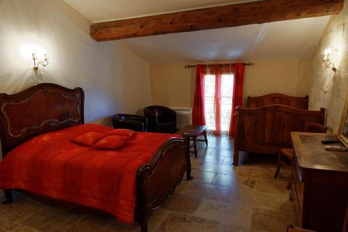 a bedroom with a bed with a red comforter at Le Mas d'Isnard in Arles
