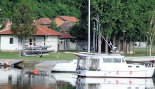 a boat is docked in the water near a house at Kafana Zlatna Ribica in Golubac