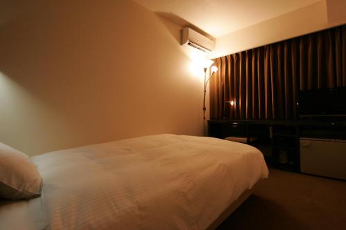 a hotel room with a white bed and a light at Green Rich Hotel Nishitetsu Ohashi Ekimae in Fukuoka