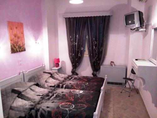 1 dormitorio con 1 cama y TV en la pared en Skiathos city views studios-apartments en Skiathos