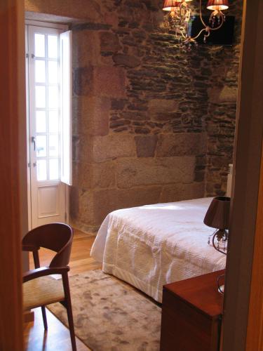 a bedroom with a bed and a chair and a window at Hotel Casa de Caldelas in Castro Caldelas