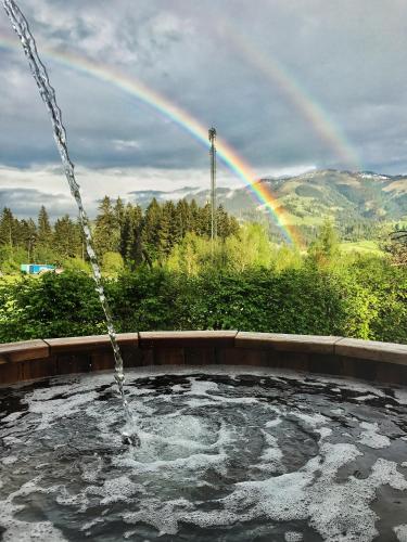 a pool with a rainbow in the background at Hotel Garni Wieshof in Kirchberg in Tirol