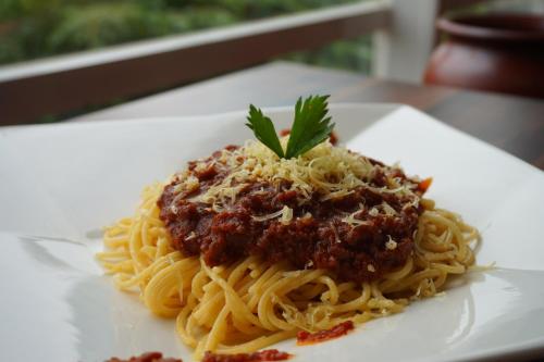 a plate of spaghetti with meat sauce on a table at Luminor Hotel Jambi Kebun Jeruk By WH in Jambi