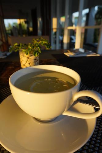 a cup of coffee sitting on a plate on a table at Luminor Hotel Jambi Kebun Jeruk By WH in Jambi