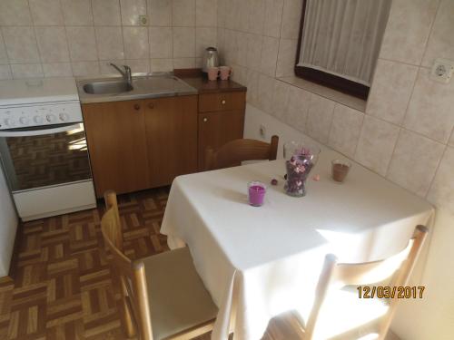 a kitchen with a table with a white table cloth at Apartmani Ledenko in Kaštela