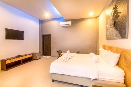 a bedroom with a large white bed with a tv at JM Hotel Kuta Lombok in Kuta Lombok
