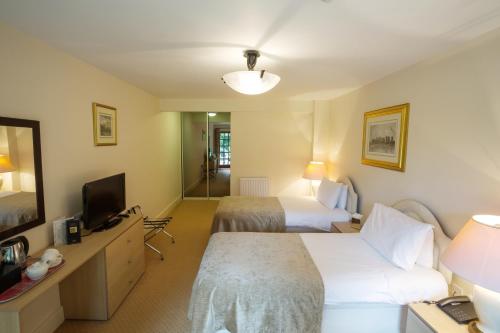 a hotel room with two beds and a television at Donnington Grove in Newbury