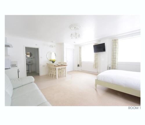 a white bedroom with a bed and a table at The Old Stables in Minehead