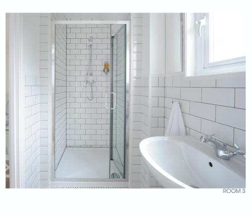 baño blanco con ducha y lavamanos en The Old Stables en Minehead