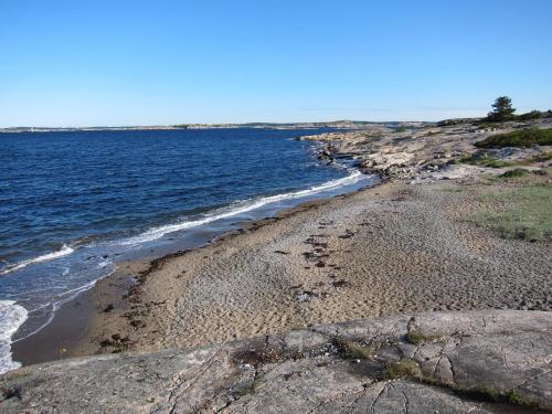 a beach with rocks and the ocean on a sunny day at Källviken Semesterby in Strömstad