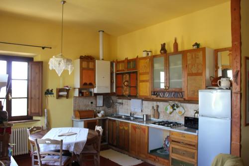 サン・ジミニャーノにあるBio Agriturismo Podere Pretoiaのキッチン(木製キャビネット、白い冷蔵庫付)
