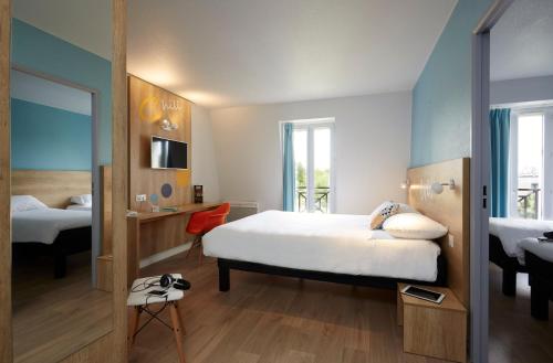 a hotel room with a bed and a mirror at Hôtel Baudouin in Valenciennes