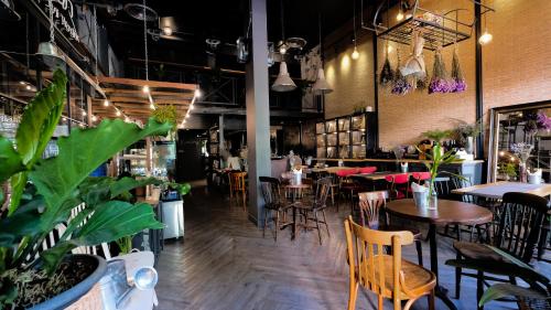 Un restaurante con mesas, sillas y plantas. en Iron32 Hotel, en Chiang Mai