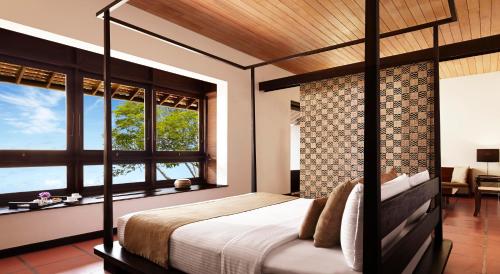 a bedroom with a bed and two windows at Jetwing Lagoon in Negombo