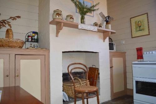 a kitchen with a fireplace with a chair and a table at Albion Cottage in Queenscliff