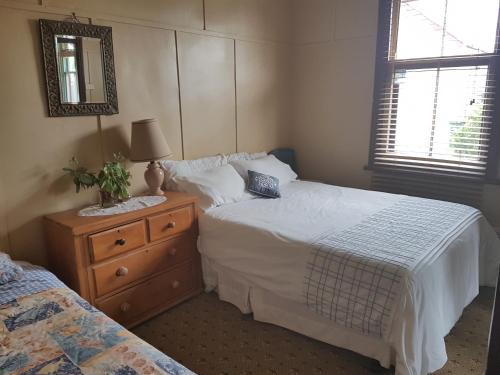 a bedroom with two beds and a dresser and a mirror at Twomey's Cottage in Queenscliff