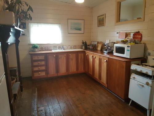 uma cozinha com armários de madeira e um micro-ondas em Twomey's Cottage em Queenscliff