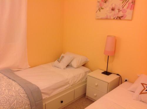 a small bedroom with a white bed and a lamp at Mojoy Homesuites At Runyon in Newark