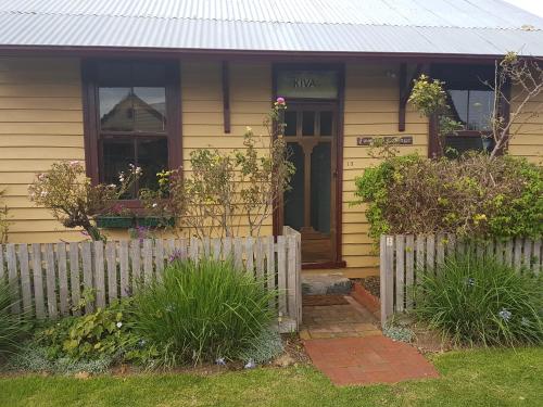 a yellow house with a white fence in front of it at Twomey's Cottage in Queenscliff