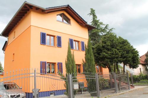 a orange house with blue shutters on a fence at Seaside Villa Leipzig in Leipzig