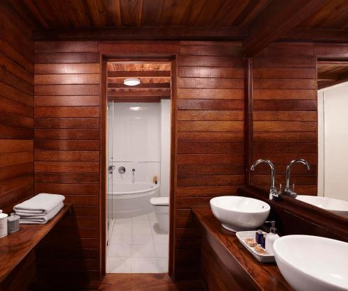 a bathroom with wooden walls and two sinks and a toilet at Jetwing St Andrew's in Nuwara Eliya