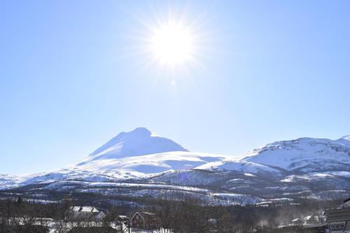 una montaña cubierta de nieve con el sol en el cielo en Lyngseidet Gjestegård, en Lyngseidet