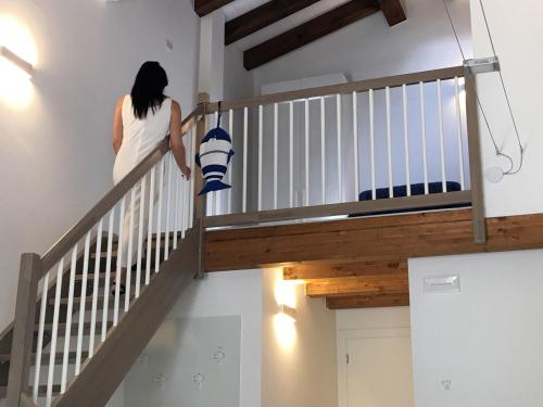 a woman walking down the stairs with a pillow at Dune Prestige & Chalets in Bibione