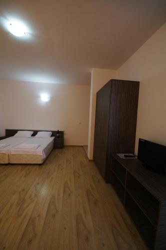 a bedroom with a bed and a desk and a television at Guest House ASK in Primorsko