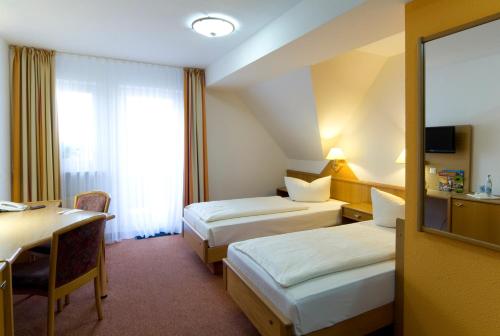 a hotel room with two beds and a desk at Hotel Sonneck in Schwäbisch Hall
