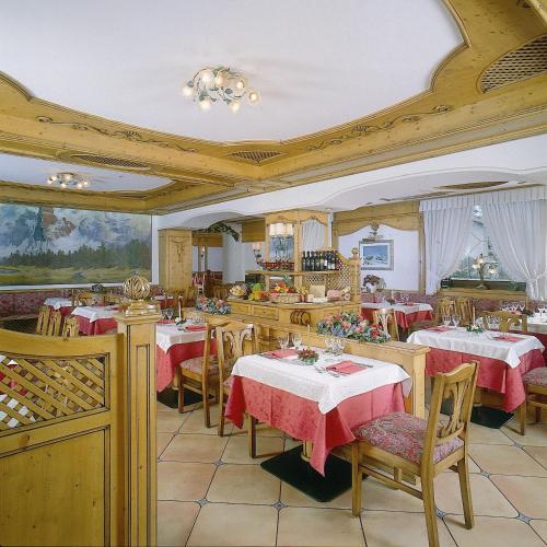 ein Restaurant mit Tischen und Stühlen mit roten Tischdecken in der Unterkunft Hotel Alpina in Pinzolo