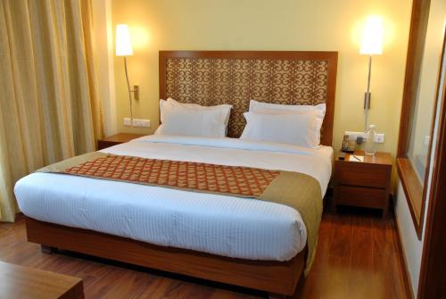 a large bed in a hotel room with two lamps at Cambay Grand Kukas in Jaipur