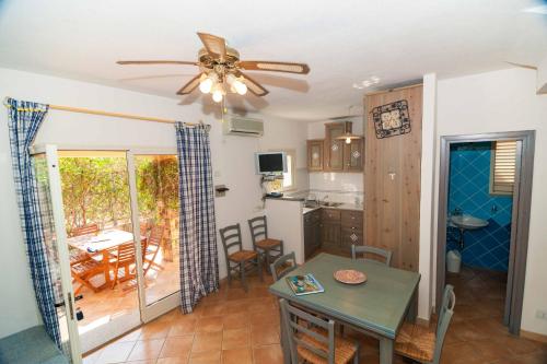 una cucina e una sala da pranzo con tavolo e ventilatore a soffitto di Casa Piras a San Teodoro