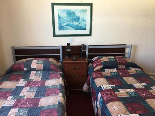 a hotel room with two beds and a picture on the wall at The Bridge Inn in Isleworth